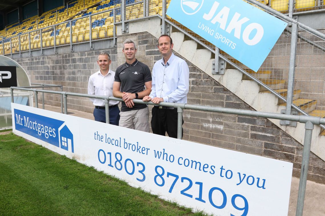 Mark Rainy and Chris Milner, Mr Mortages, with Aaron Downes, Torquay United, in front of our new signage at Plainmoor.