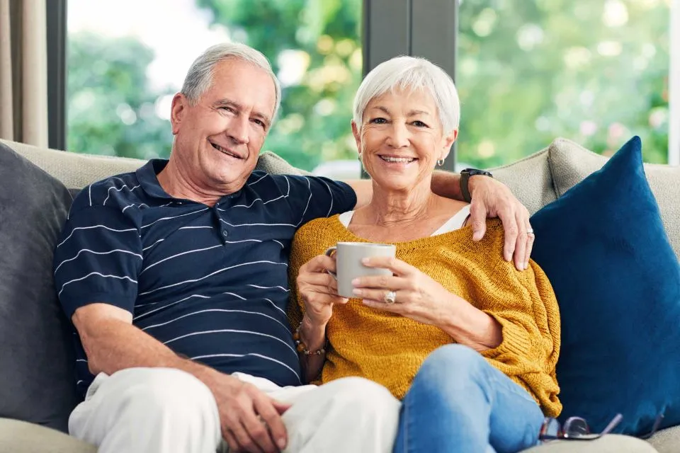 Older couple sitting on sofa. Enjoying their home after Equity release